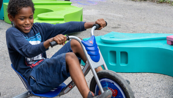 young boy rides a tricycle