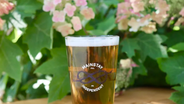 A beer with flowers behind it.
