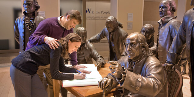 Folks posing with statues of Founding Fathers at National Constitution Center