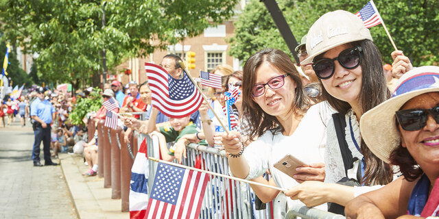 Parade watchers smiling and waving American flags