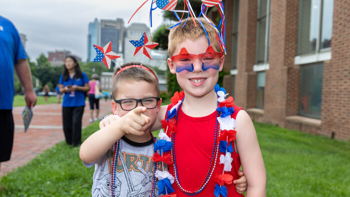 Two children in festive outfits smiling in front of the Independence Visitor Center. 