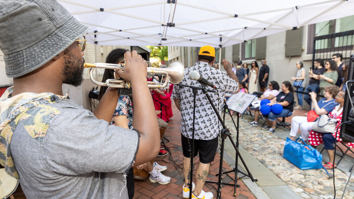 Person wearing hat playing the trumpet for visitors. 