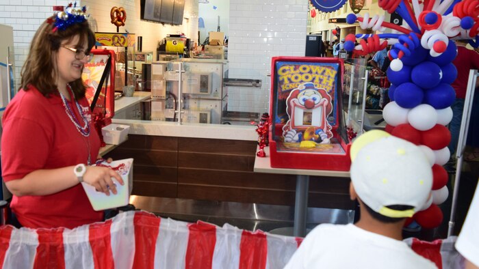 Child playing "Clown tooth Knockout" while attendant happily watches