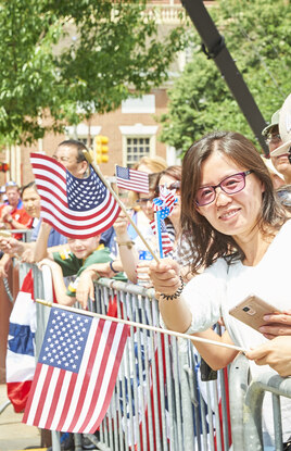 Parade watchers smiling and waving American flags